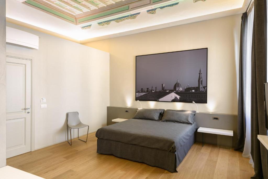 蒙特瓦尔基Palazzo Vasarri - Luxury design suites的卧室配有一张床,墙上配有电视。