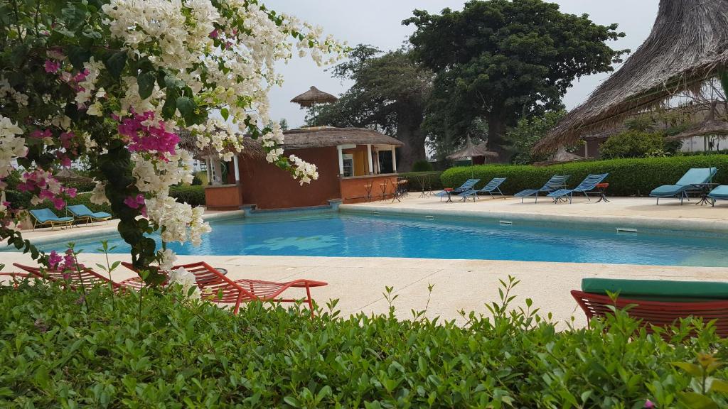 Sinndia猴面包树日光酒店的一个带草坪椅和鲜花的游泳池