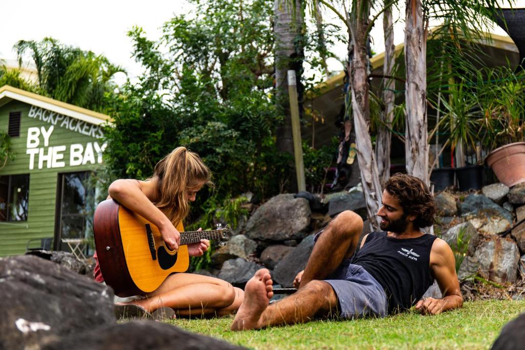 埃尔利海滩海湾背包客旅馆的男人和女人在草地上弹吉他