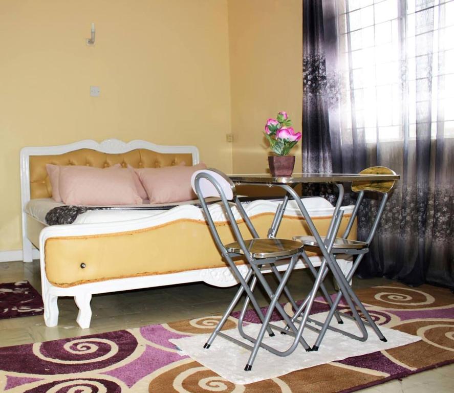 内罗毕Kenya Inn的卧室配有一张床和一张桌子及椅子