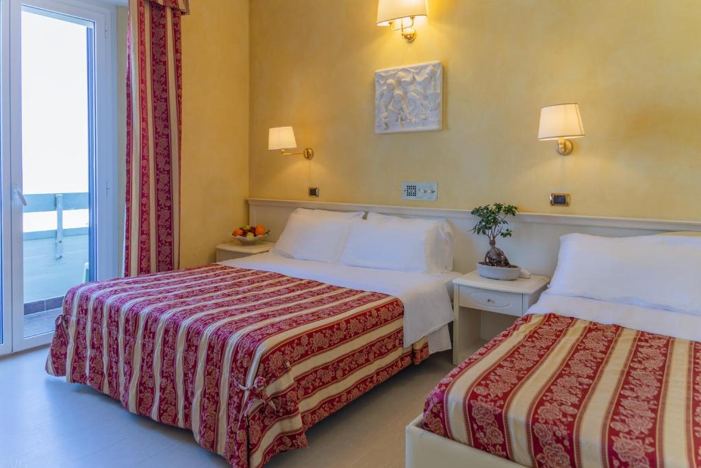 里米尼菲奥里塔行政酒店的酒店客房设有两张床和窗户。