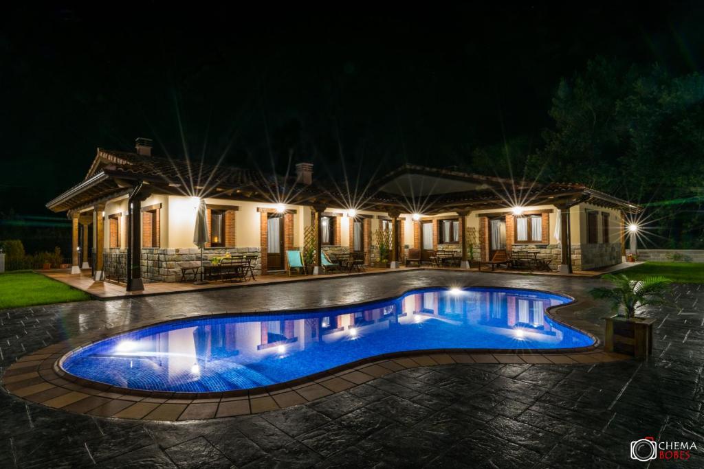 OviñanaLas Carriles Apartamentos rurales的夜间在房子前面的游泳池