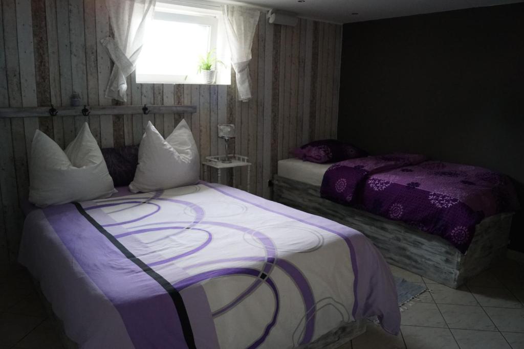 MellenseeFerienwohnung Rehagen Süd的一间卧室设有两张带紫色床单的床和窗户。