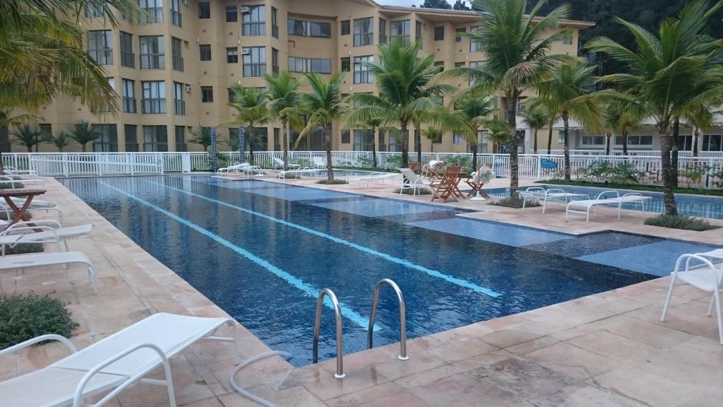 曼加拉蒂巴Loft com Praia的棕榈树和建筑的酒店游泳池