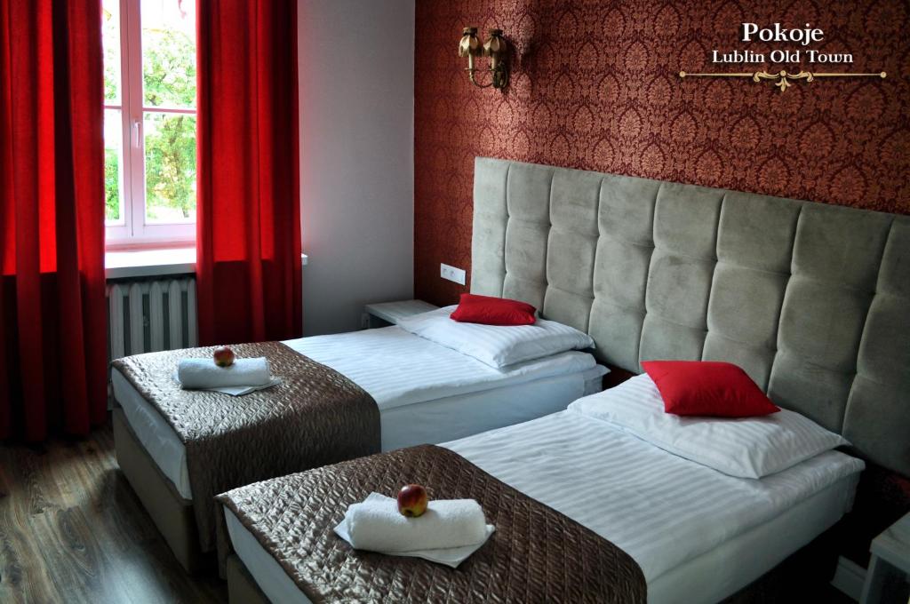 卢布林Lublin Old Town Rooms的配有红色窗帘的酒店客房的两张床
