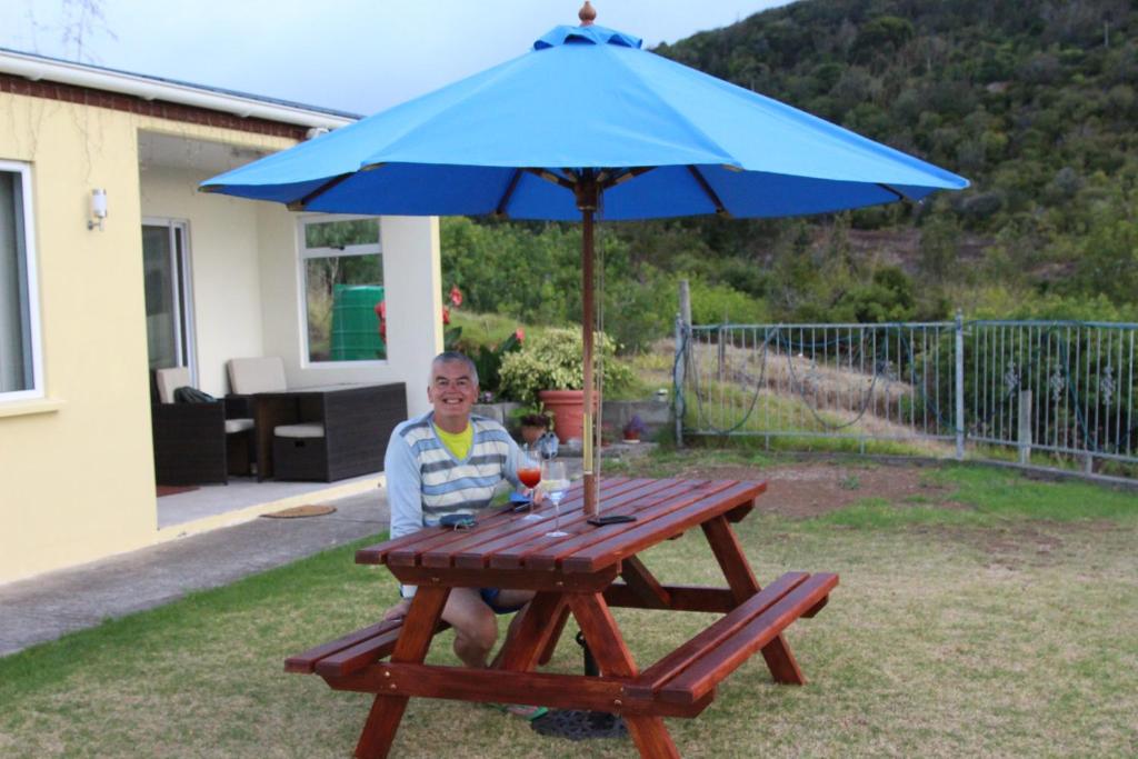 JamestownRichards Travel Lodge的坐在野餐桌上,戴着蓝伞的女人
