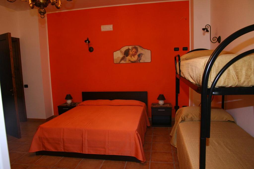 Acquarica艾拉特费努酒店的一间卧室设有两张双层床和橙色的墙壁