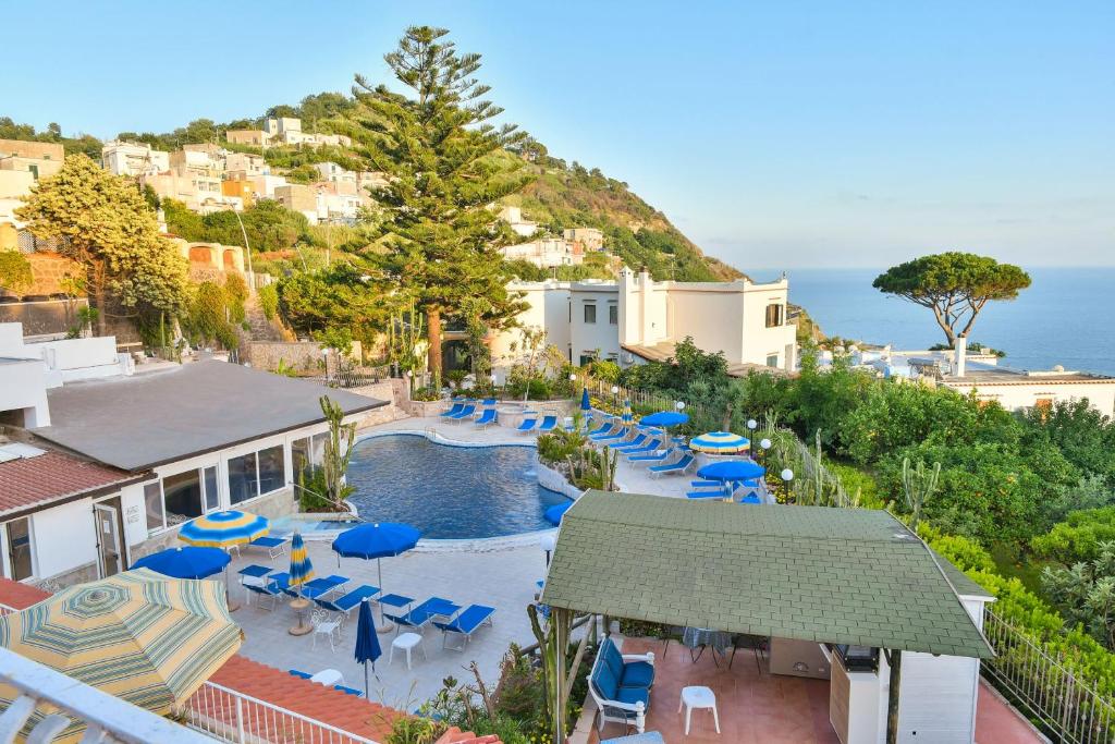 伊斯基亚圣拉斐尔温泉酒店的一个带椅子和遮阳伞的游泳池以及大海