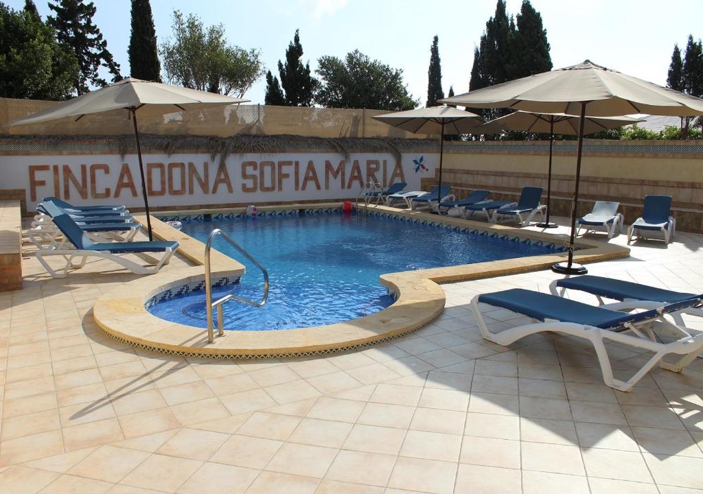 圣佩德罗-德尔皮纳塔尔芬卡多纳索非亚玛丽亚公寓的庭院内一个带椅子和遮阳伞的游泳池
