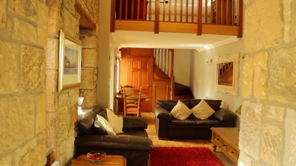 巴洛赫Smiddy Lodge的带沙发和石墙的客厅