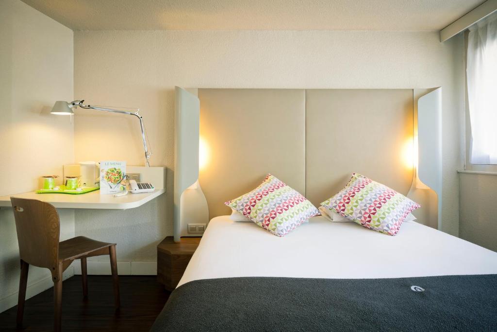 费内-伏尔泰钟楼杰内夫菲内伏尔泰酒店的一间卧室配有一张带枕头的床和一张书桌