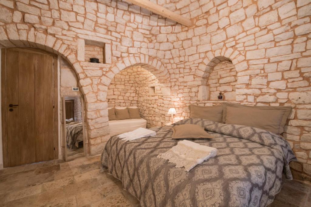 阿尔贝罗贝洛Trulli Antichi Mestieri - Widespread Trulli in the historic center的卧室配有一张石墙内的大床
