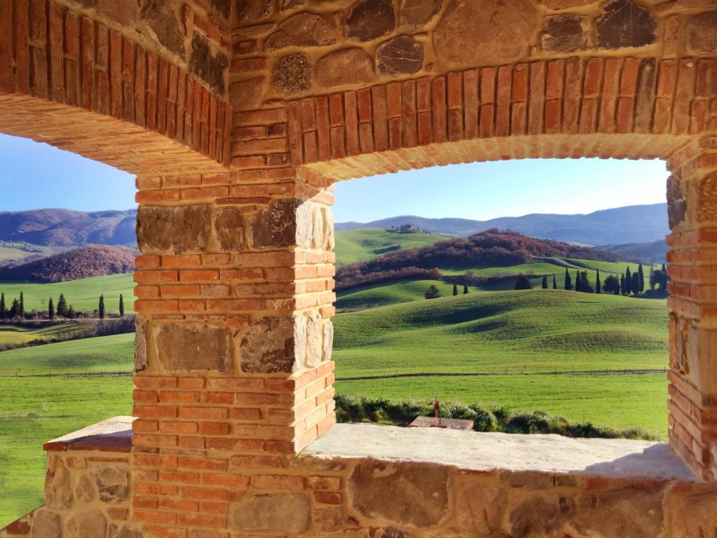 皮恩扎RELAIS VAL D'ORCIA的砖墙的窗户,眺望着绿色的田野