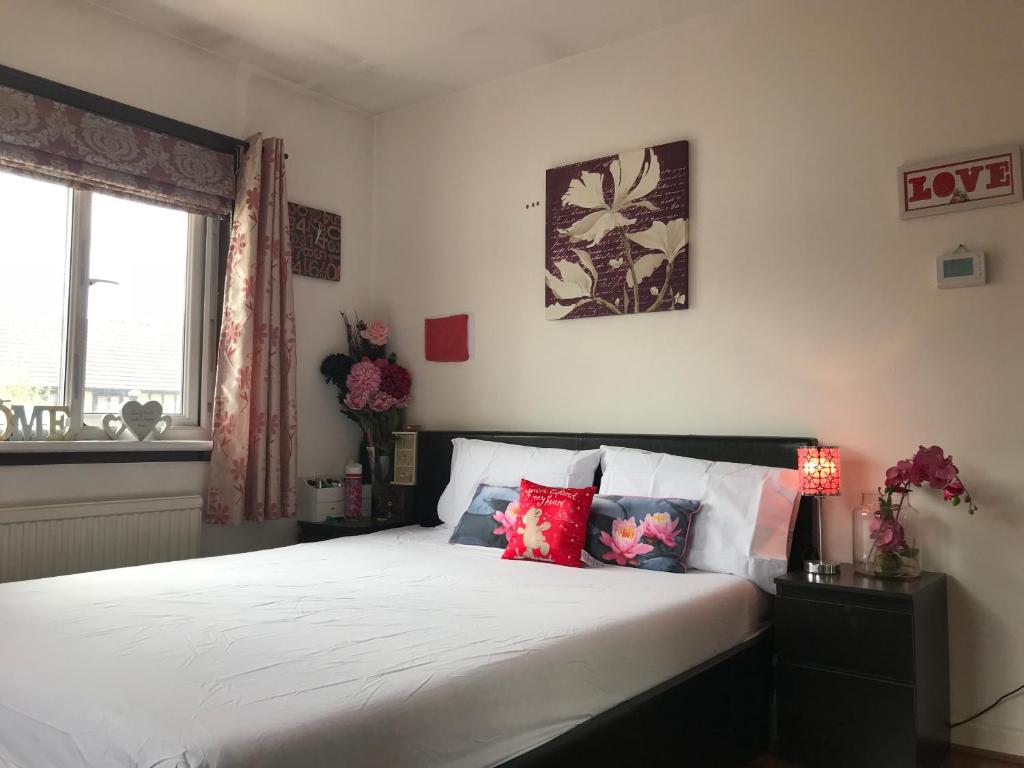伦敦宽敞的度假屋 - 15分钟到金丝雀码头/ O2 / Excel /伦敦市中心的一间卧室配有带白色床单和红色枕头的床。