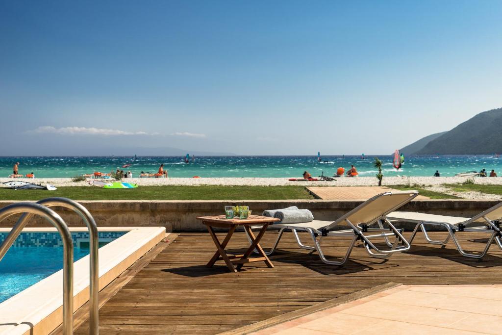瓦西利基Aktes villas的海滩旁的游泳池配有两把椅子和一张桌子