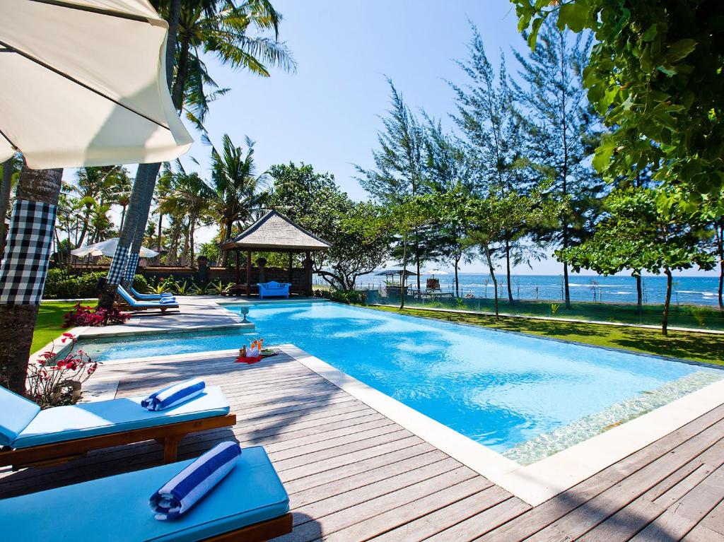 克拉玛斯Villa Puri Nirwana的一个带椅子和遮阳伞的游泳池以及大海