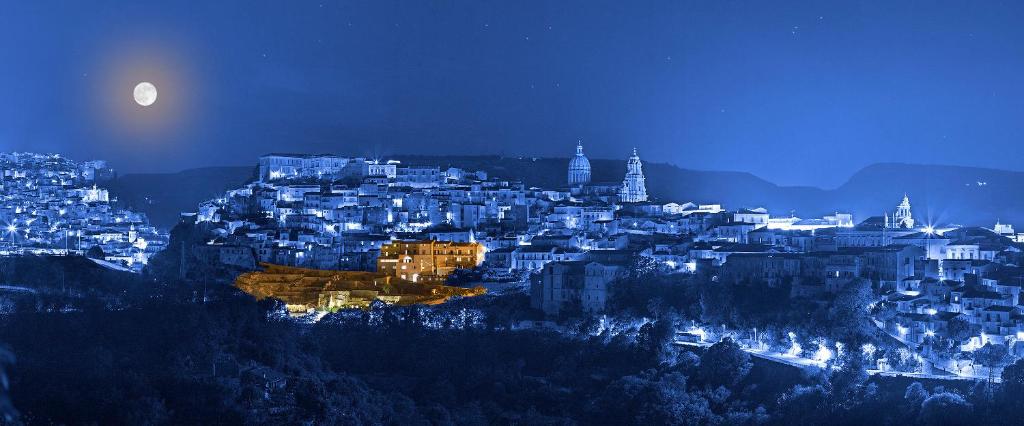 拉古萨San Giorgio Palace Hotel Ragusa Ibla的夜晚城市与月亮的景观