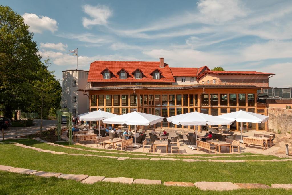 巴特阿罗尔森Hotel Brunnenhaus Schloss Landau的前面有桌子和白色遮阳伞的建筑