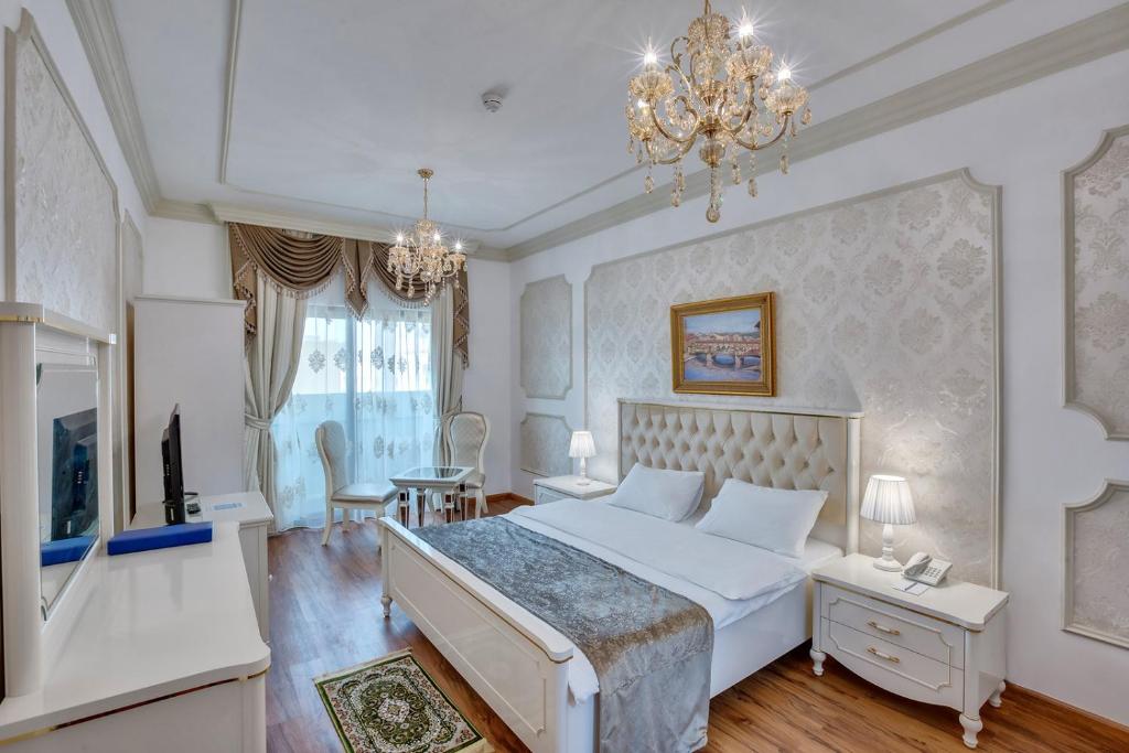 沙迦Royal Hotel的卧室配有一张白色大床和吊灯。
