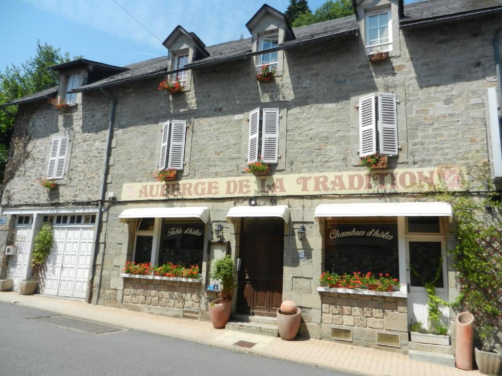 科雷兹Auberge de la Tradition的一座古老的石头建筑,窗户上有鲜花