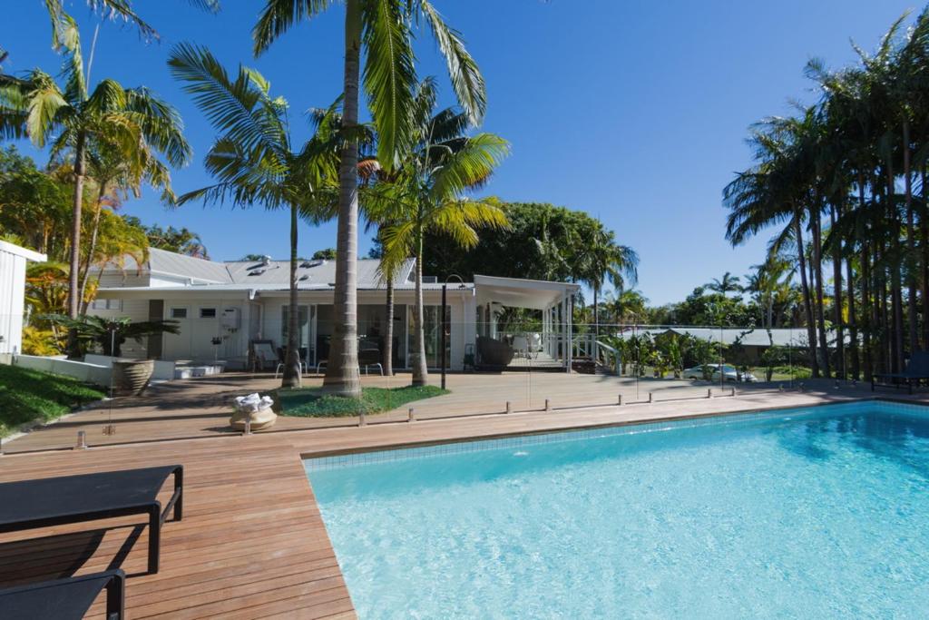 拜伦湾拜伦泉酒店的棕榈树屋前的游泳池