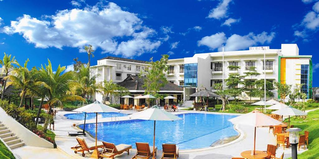巴图萨马拉度假酒店的酒店前方的游泳池配有椅子和遮阳伞