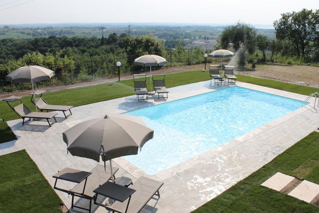 帕斯特伦戈Poggio di Pastrengo的享有带椅子和遮阳伞的游泳池的上方景色