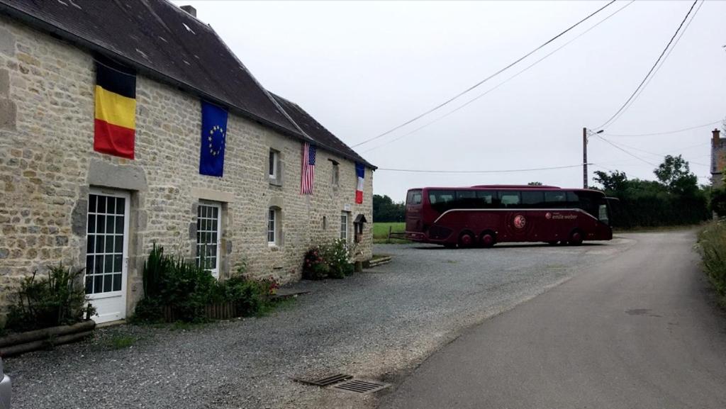 Liesville-sur-Douvechevrerie de la huberdiere的停在有旗帜的建筑旁边的红色公共汽车