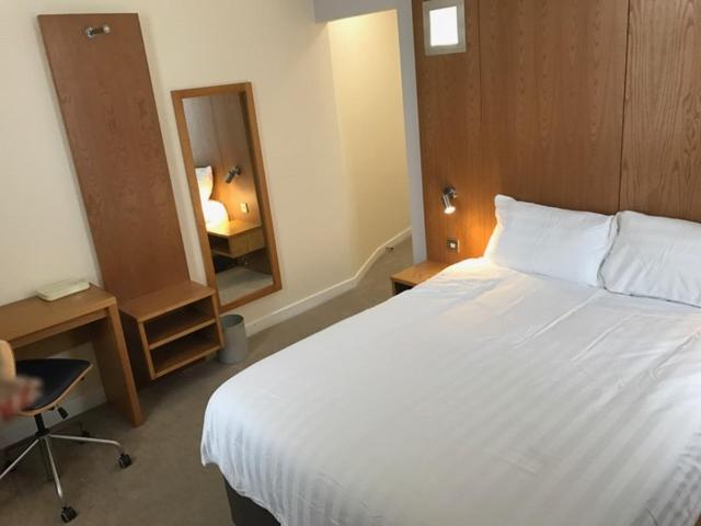 罗瑟勒姆Corona Hotel Rotherham Sheffield Meadowhall的卧室配有一张白色大床和镜子