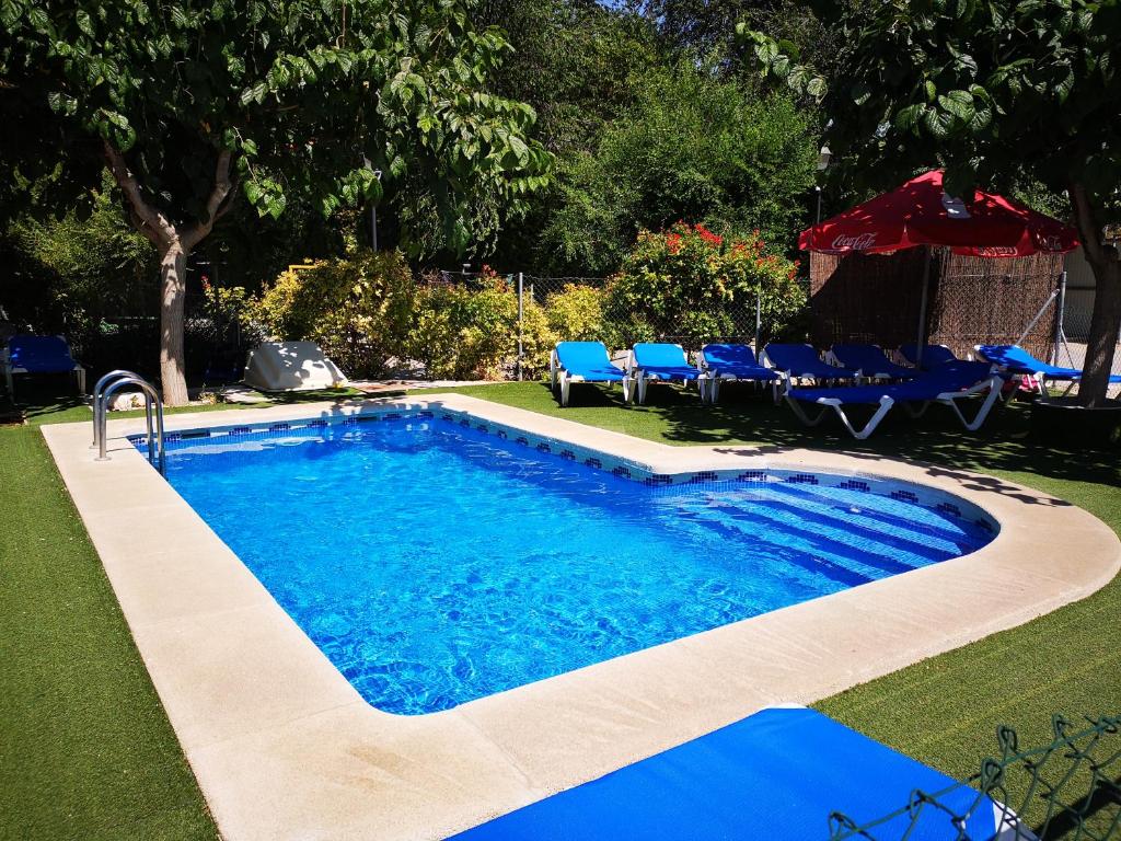 巴尔德甘加Casas Rurales Huerto Del Abuelito的庭院内一个带蓝色桌椅的游泳池