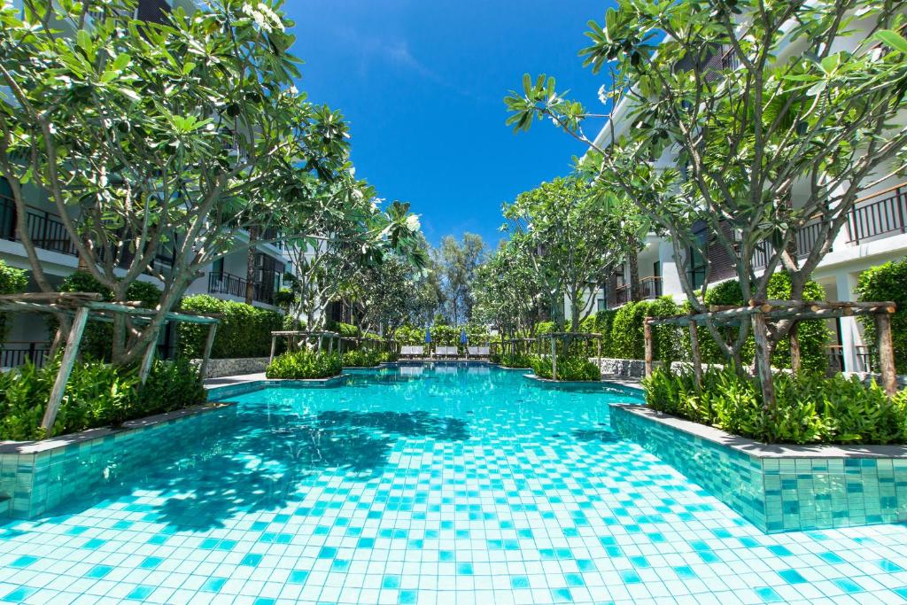 拉威海滩普吉岛标题精品公寓的一座树木繁茂的建筑中间的游泳池