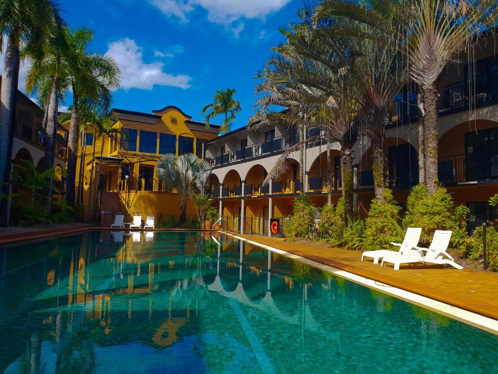 凯恩斯凯恩斯皇家棕榈酒店的棕榈树建筑前的游泳池