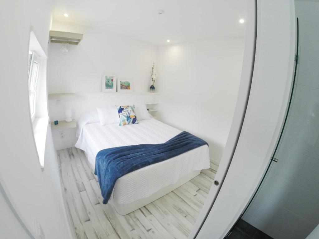 波尔图Casa d'Avó的一间白色的小卧室,卧室内配有一张床铺