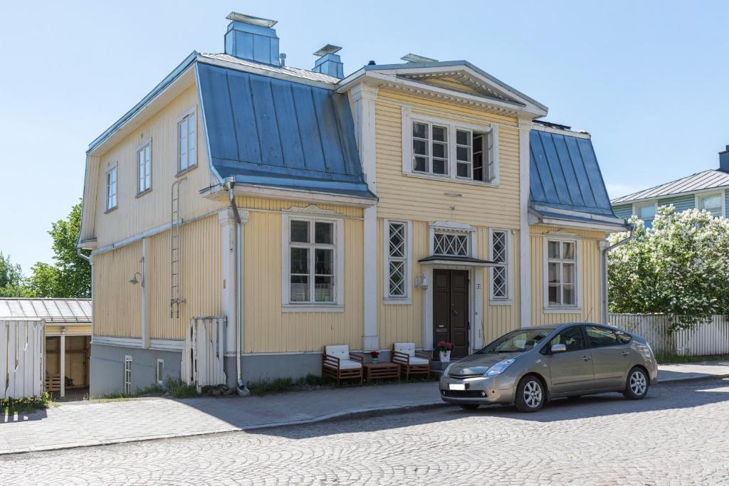 海门林纳Matin ja Maijan Majatalo的停在黄色房子前面的蓝色屋顶的汽车