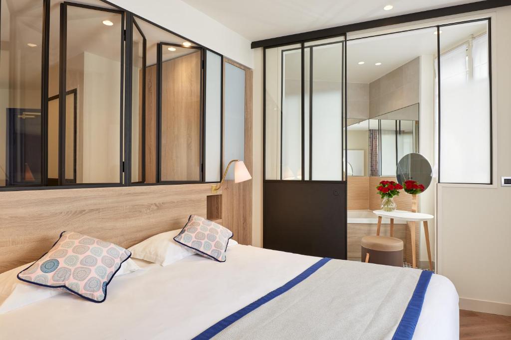 巴黎希维内酒店的一间卧室设有床铺和玻璃墙