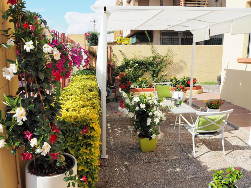 蒂勒尼亚Residence Hotel Vittoria的庭院里种有鲜花,配有白色的遮阳伞和椅子