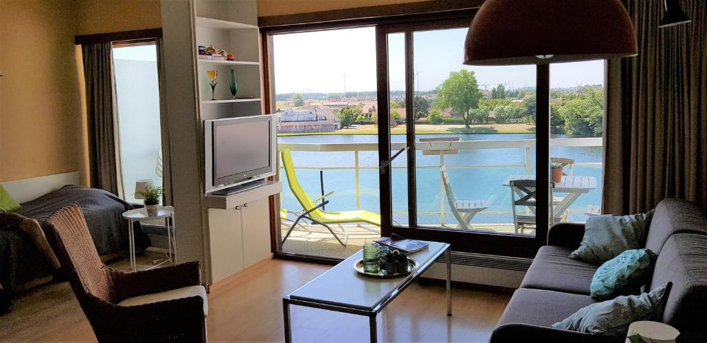 克诺克－海斯特Duinbergen Laguna Beach的带沙发和电视的客厅以及阳台。