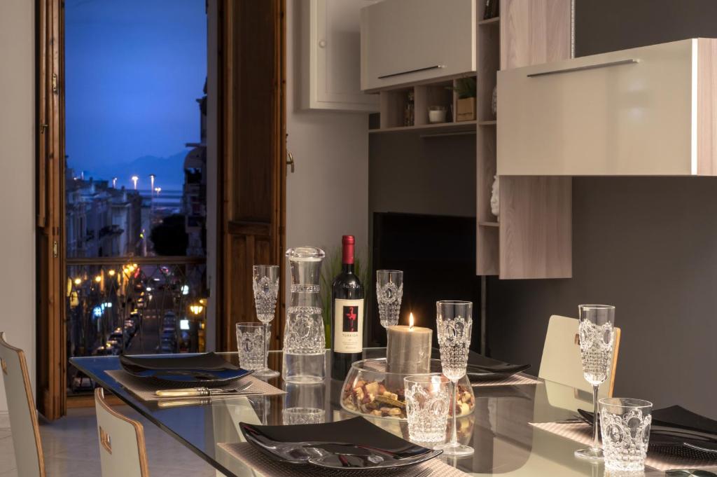 卡利亚里La Casa nel Corso的厨房配有玻璃桌、葡萄酒瓶和玻璃杯