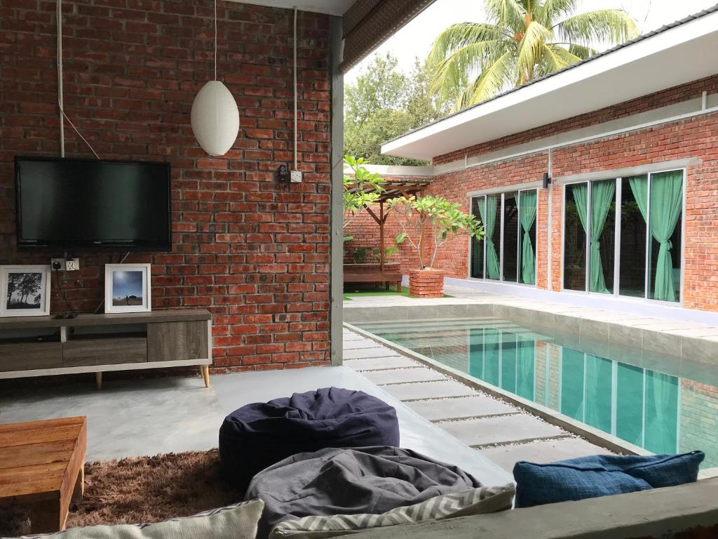 Huma丹绒鲁泳池TRV度假屋的带电视的客厅和游泳池。