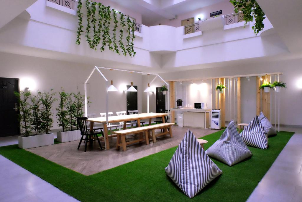 合艾Siam Mansion - SHA的客厅配有桌子和绿色地毯。