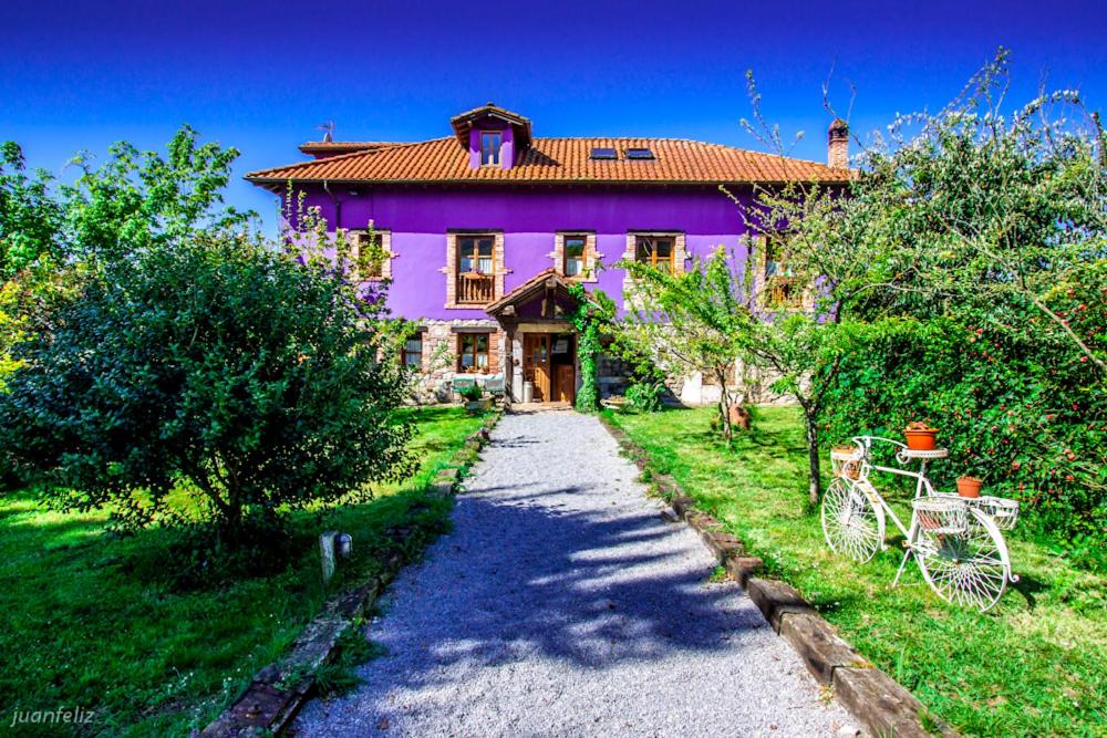 BodeEl Búho de la Remolina的一座紫色的房子,前面有一条碎石路