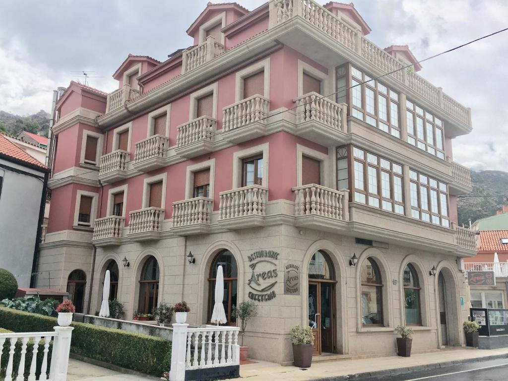 O Pindo阿里亚斯酒店的前面有白色围栏的粉红色建筑