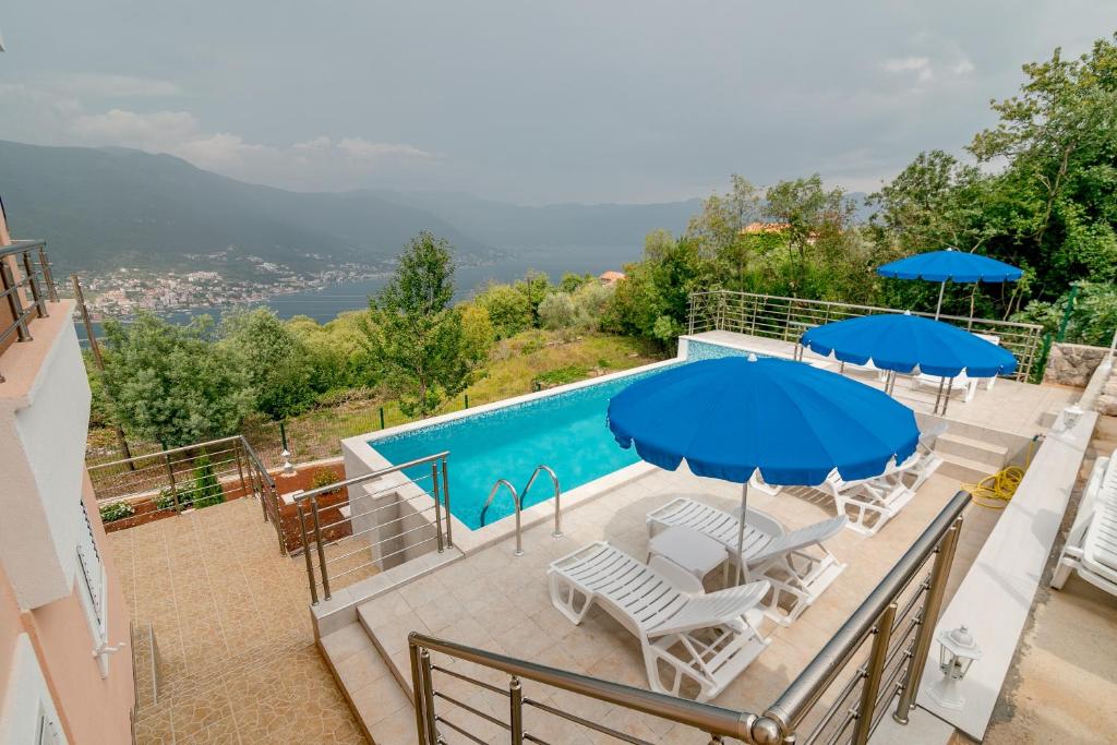 卢什蒂卡Apartments Mitrovic的一个带椅子和遮阳伞的游泳池和一个游泳池