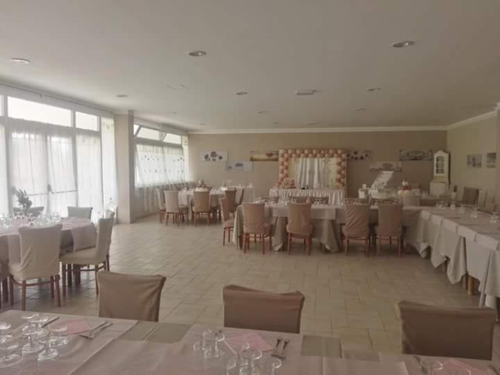 阿普里利亚Agriturismo "Lo zafferano"的宴会厅配有白色的桌椅