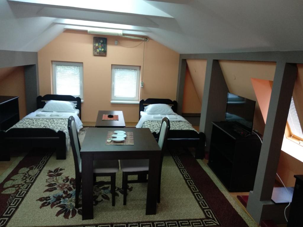 尼什Small Apartment at center of the city的客房设有两张床、一张桌子和一张桌子以及椅子。