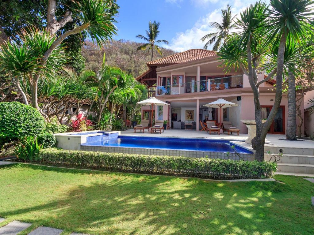 甘地达萨Villa Pantai Candidasa的一座带游泳池和棕榈树的房子
