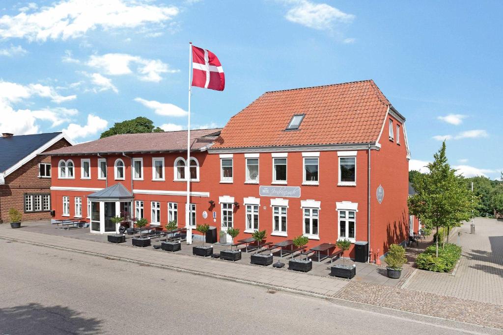 基巴埃克Hotel Jernbanegade的一座红色的建筑,上面有旗帜