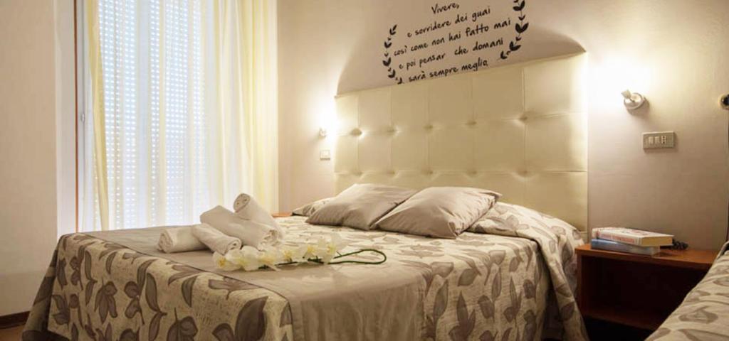 里米尼桑德拉酒店的一间卧室配有一张铺有白色床单和鲜花的床。