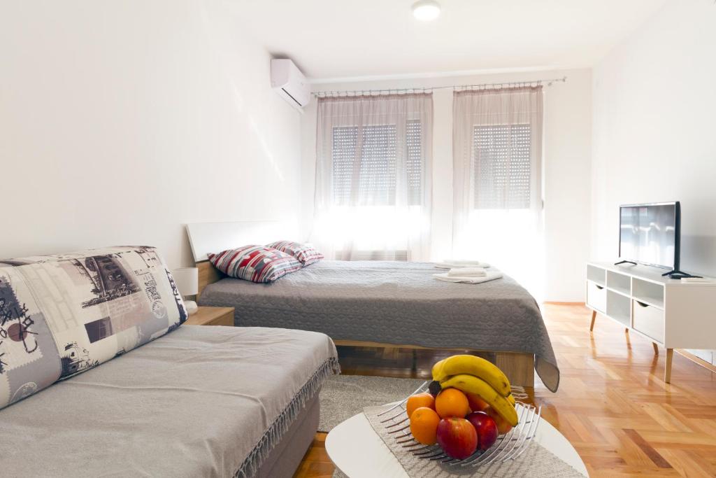 尼什Tea Studio Apartments的客厅配有两张床和一张带水果的桌子。