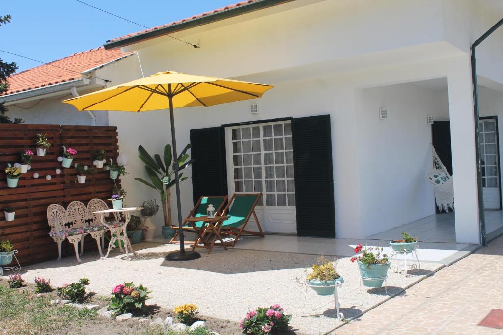 阿威罗Casa das Camélias的庭院配有遮阳伞、椅子和桌子。
